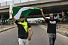 A photo of two protesters holding the Nigerian flag on the road.