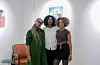 Artist Tsion Mehari stands between Nafkot Gebeyehu and Zion Yaynu at the opening of her solo exhibition, By a Thread, at Studio 11. The trio smiles in front of Mehari\u2019s artwork.