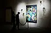 Two people in the shadows observe an abstract painting on the wall.
