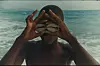 A still from Julianknxx\u2019s short film \u2018Temple Run,\u2019 showing a young boy covering his eyes with two seashells.