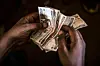 A market trader counts Kenyan shilling banknotes