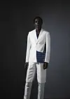A man poses for a photo wearing a white suit with Akwete fabric attached to its side.