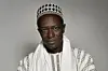 An image of Moussa S\u00e8ne Absa dressed in traditional attire looking at the camera.