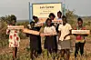 South Sudanese women in Rhino Camp holding up signs with song names.
