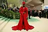 Wisdom Kaye wears a red floor length blazer with floral details and a matching hat at the 2024 MET Gala.