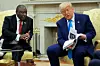 South African President Cyril Ramaphosa sits beside former U.S. President Donald Trump in the Oval Office, as Trump flips through a document during a diplomatic meeting.