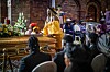 A still from the TV series, of a woman dressed in yellow standing at a coffin.