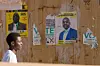 A man passes by a wall displaying campaign posters of President Emmerson Mnangagwa and his rival Nelson Chamisa during Zimbabwe's 2023 general election voter education campaign by a local civil society organisation in Harare, Zimbabwe.