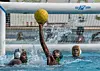 A photo of a teenage water polo player stretching to catch the ball.