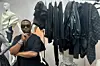 A photo of David Tlale in his New York showroom with some of his pieces on a hanger to his left.