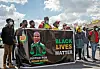Protesters parading a banner that reads 'Justice For Lindani Myeni — Black Lives Matter'.