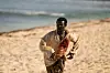 A man in a torn, bloodied shirt is seen running on the beach.
