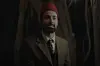 Ahmed Hatem starring as Omar Affendi, wearing a gray suit and red tarboush.