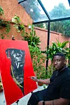 A daylight shot of artist Anthony Azekwoh next to his most famous painting, “The Red Man.”