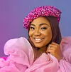 Mercy Chinwo faces the camera with a smile, wearing a pink chiffon dress