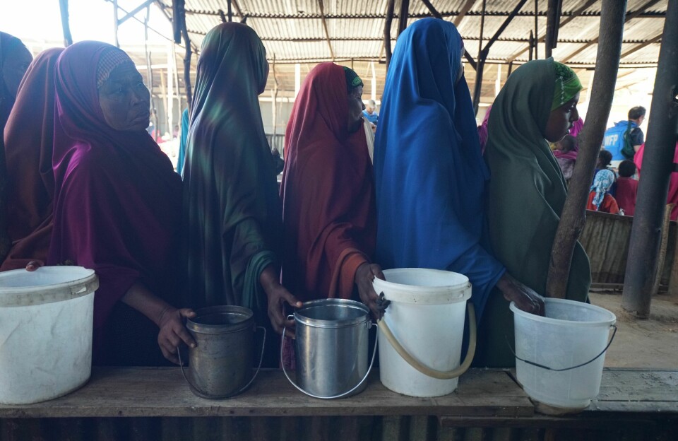 Somali women wait in line at a World Food Program 'wet food' distribution center in central Mogadishu. Somali women waiting in a food line with different types of containers.