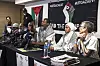 Six South African activists seated at a long table with microphones in front of them. Mandla Mandela gestures with his hand as he speaks.