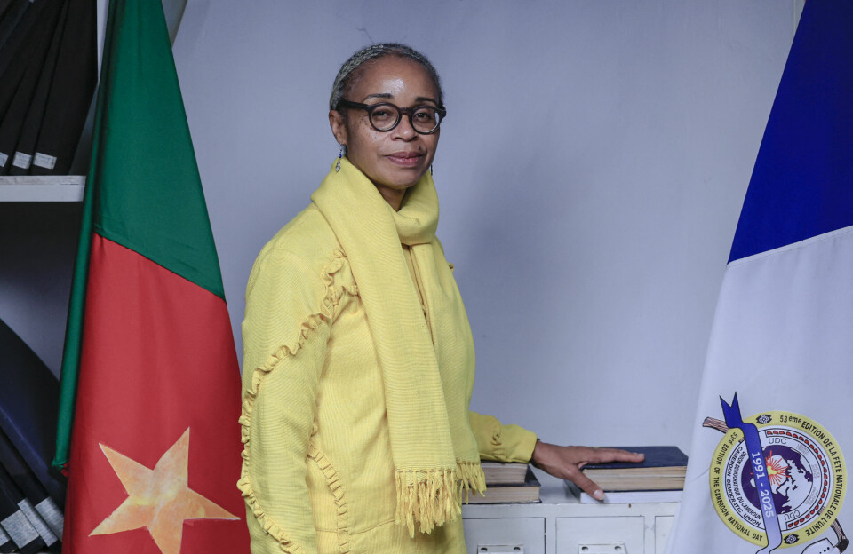Cameroon Democratic Union (UDC) presidential candidate, and the mayor of the city of Foumban, Hermine Patricia Tomaino Njoya, is the only woman in Cameroon’s Oct. 12 presidential race. Hermine Patricia Tomaino Njoya, in a yellow outfit, stands between two flags, smiling at the camera, and her hand on a book.