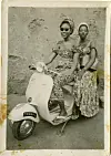 A sepia-colored image of two women on a stationary motorbike.