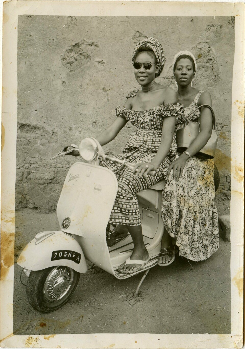 Seydou Keita. Untitled, 1957. A sepia-colored image of two women on a stationary motorbike.