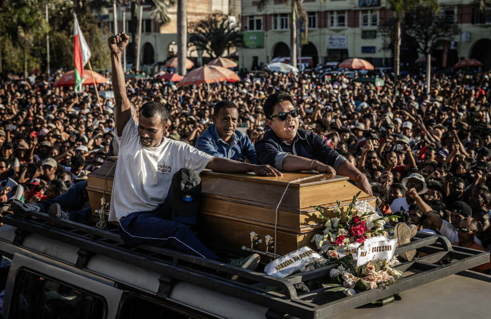 Family members of a protester killed during the uprising in Madagascar carry the casket atop a van, surrounded by protesters and residents during a rally demanding the resignation of President Andry Rajoelina in Antananarivo, on October 13, 2025 A casket of a protestor killed during marches sits atop a van with three men, one with his fist in the air. They are surrounded by a throng of people who also have their fists in the air.