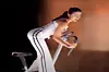 Egyptian singer Ruby is wearing white jogging pants and a white top while on an exercise bike.