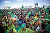 A crowd of people waves flags and chants slogans during a rally