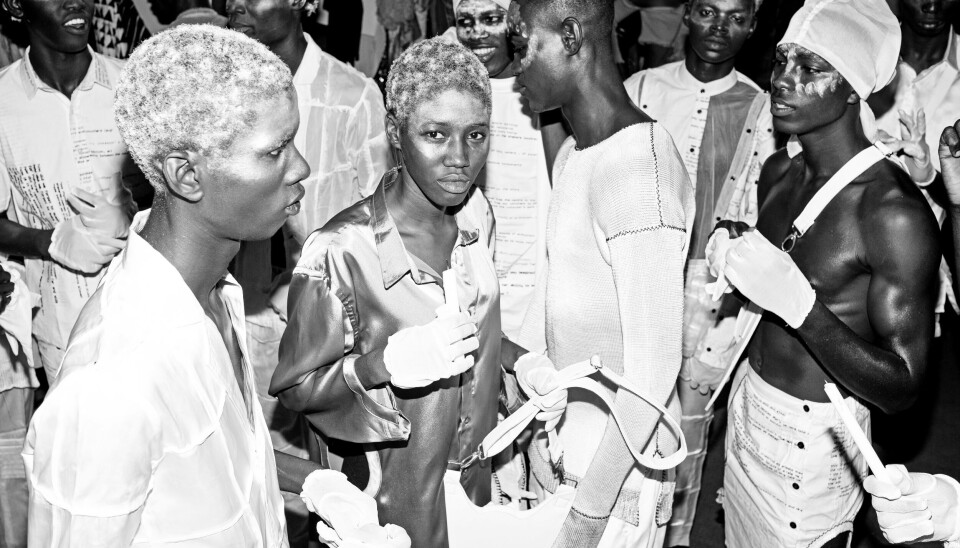 “As I went into this, it really helped me grow in terms of perspective, and I let the story define itself.” A black and white photo of a group of models preparing for the runway at a fashion show.