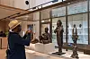 A man wearing a hat stands in front of sculptures at the MOWAA gallery in Benin, photographing them.
