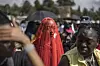 A young woman covered in a red veil stares at the camera. She’s standing in the middle of a demonstration held to protest gender-based violence and femicide in South Africa.