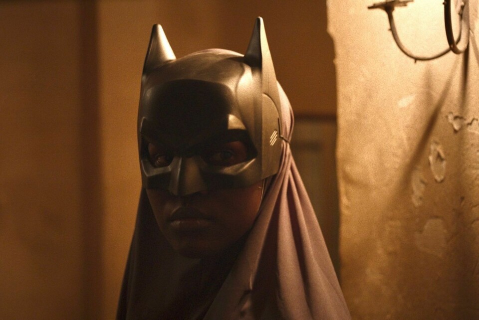 Deux ans après avoir présenté son court métrage, I Promise You Paradise à Cannes, Morad Mostafa revient avec son premier long métrage, un regard singulier sur la crise migratoire en Egypte. Une femme noire portant un voile gris et un masque de super-héros se tient debout dans la faible lumière d'une lampe.