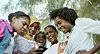 Five teenage girls are looking down at a phone screen, laughing and looking disgusted.