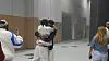 Yago and Moe are hugging each other in a hall, Moe is wearing a black shirt and Yago a white shirt.