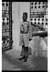 A posed portrait of a decorated officer at the Osu/Christiansborg Castle. He wears a fex (a red, cylindrical hat or cap with a tassel), usually worn by escort policemen and other officials during colonial rule.