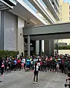Emily Chepkor stands in front of a large crowd of runners outside a building, preparing to lead a run.