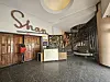The lobby of the Sarakasi Dome in Nairobi, showing the original vintage “Shan” sign above wooden doors, a reception desk, colorful art displays, and a spiral staircase with a mural-covered wall in the background.