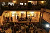 View of a bustling courtyard at night, with people gathered on three floors of a building during an event at Kali Works in Ngara.