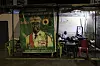 Residents watch television next to a poster depicting Guinea President Mamady Doumbouya