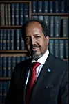 Somalia’s President, Hassan Sheikh Mohamud, stands in front of a bookshelf and smiles at the camera.