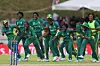 A group of Nigerian under-19 women’s cricket players in green uniforms celebrating on the field after winning a match.