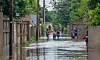 A group of men and women wade through floodwater carrying belongings in a residential area in Maputo Province, Mozambique.