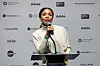 Olive Nwosu, wearing a white turtleneck, is speaking into a mic at Sundance Film Festival 2026.
