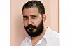 A portrait of Morad Mostafa, an Egyptian man with dark brown hair and a full beard, wearing a white shirt.