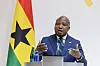 Ghana's Minister of Foreign Affairs, Samuel Okudzeto Ablakwa, gestures with both hands as he speaks at a podium with the Ghanaian flag behind him.