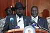 South Sudan's President Salva Kiir stands at a podium and gives a press conference alongside his former vice-president and political rival, Riek Machar, standing slightly behind him.