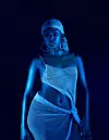 Blue-lit studio portrait of Karun wearing a sparkling mesh headscarf and a matching two-piece outfit.