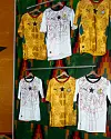 Three football jerseys on hangers, two are yellow with a black star in the middle, and one is white with a black star in the middle.