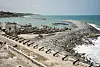 A view of the Cape Coast Castle, a former slave holding facility, in Cape Coast, Ghana. Canons, boats, and the ocean are visible in the image.