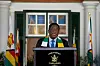 Zimbabwe President Emmerson Mnangagwa stands at a podium with the “President Zimbabwe” seal on it.