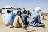 Sudanese refugees at Oure Cassoni camp in Chad, seated on the ground, facing away from the camera, except for a boy who looks back at the camera.